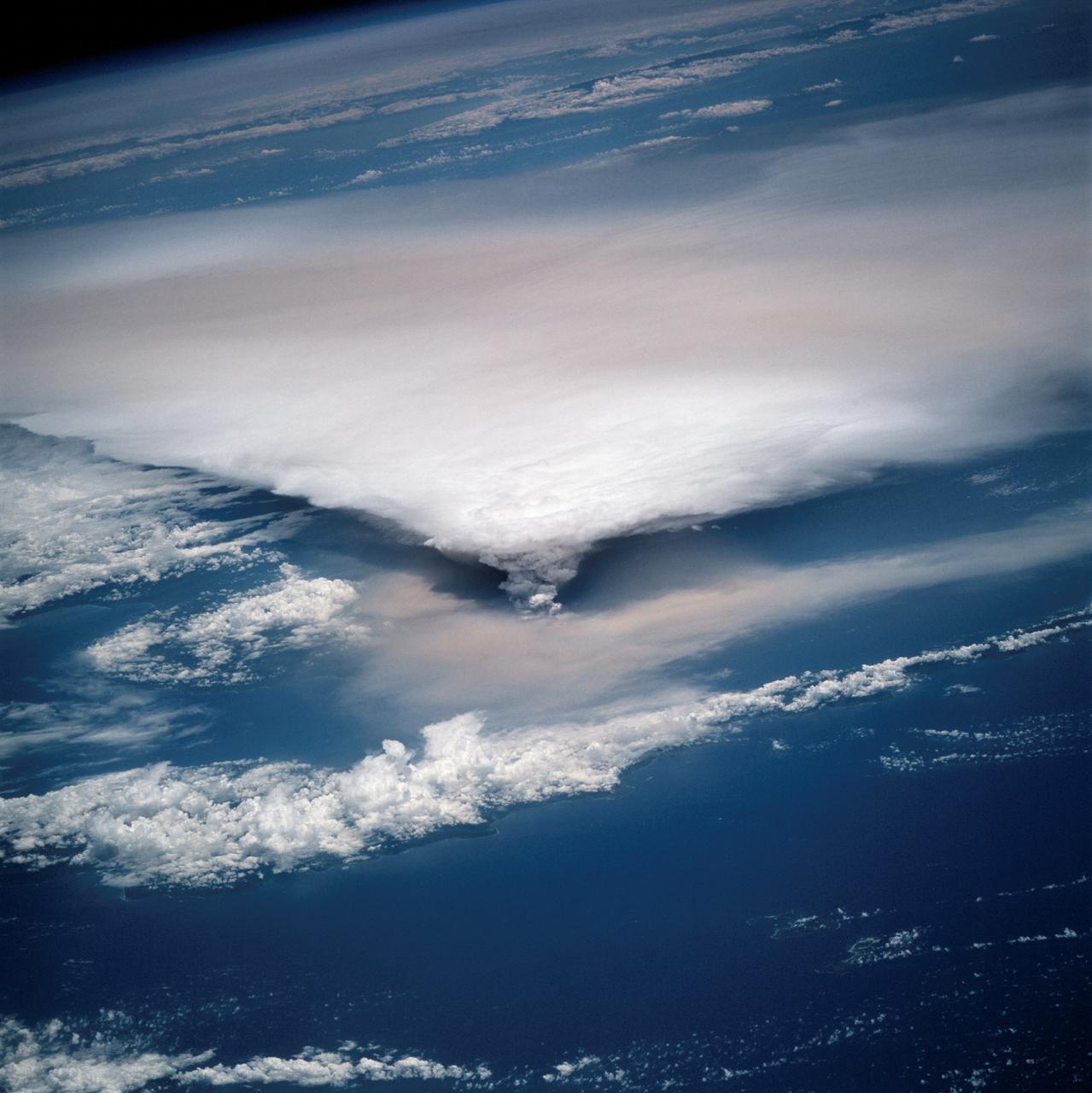 STS064-116-064 (20 Sept. 1994) --- Near the end of the mission, the crew aboard space shuttle Discovery was able to document the beginning of the second day of activity of the Rabaul volcano, on the east end of New Britain. On the morning of Sept. 19, 1994, two volcanic cones on the opposite sides of the 6-kilometer sea crater had begun to erupt with very little warning. Discovery flew just east of the eruption roughly 24 hours after it started and near the peak of its activity.  New Ireland, the cloud-covered area in the foreground, lies just east of Rabaul harbor. The eruption, which sent a plume up to over 60,000 feet into the atmosphere, caused over 50,000 people to evacuate the area. Because winds were light at the time of the eruption, most of the ash was deposited in a region within 20 kilometers of the eruption zone. This photo shows the large white billowing eruption plume is carried in a westerly direction by the weak prevailing winds. At the base of the eruption column is a layer of yellow-brown ash being distributed by lower level winds. A sharp boundary moving outward from the center of the eruption in the lower cloud is a pulse of laterally-moving ash which results from a volcanic explosion. Geologists theorize that the large white column and the lower gray cloud are likely from the two main vents on each side of the harbor. The bay and harbor of Rabaul are covered with a layer of ash, possibly partly infilled with volcanic material. Matupit Island and the airport runway have disappeared into the bay. More than a meter of ash has fallen upon the city of Rabaul. Up to five vents were reported to have erupted at once, including the two cones Vulcan and Tavurvur, which are opposites of the harbor as well as new vents below the bay. Half of the Vulcan cone has collapsed into the sea. The extra day in space due to bad weather at the landing site afforded the crew the opportunity for both still and video coverage of the event. Photo credit: NASA or National Aeronautics and Space Administration
