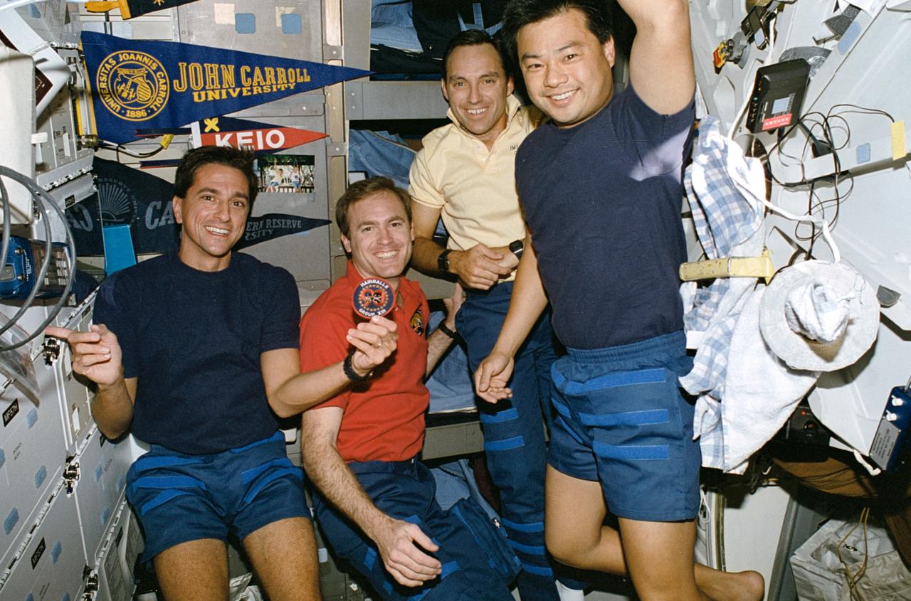 STS065-18-022 (8-23 July 1994) --- During off-duty time on the Space Shuttle Columbia's mid-deck, four members of the crew, from the 1990 (thirteenth) astronaut class, display their group's insignia.  The "hairballs" pictured, (left to right) are astronauts Donald A. Thomas, James D. Halsell, Jr., Carl E. Walz and Leroy Chiao.