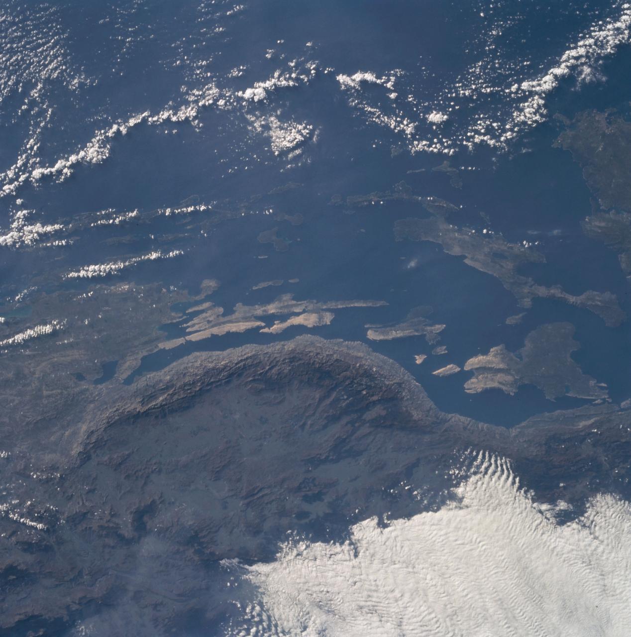 The Adriatic coast of Bosnia-Herzegovina and Croatia is centered at approximately 44.5 degrees north and 15.0 degrees east. North is at the bottom of the frame. The town of Bihac is located under the cloud layer in the center left of the frame. The terrain is composed of limestone and the geomorphic term "karst" is named after the city in the area. The Velebit Mountains form the ruggedd coast in the center of the frame.