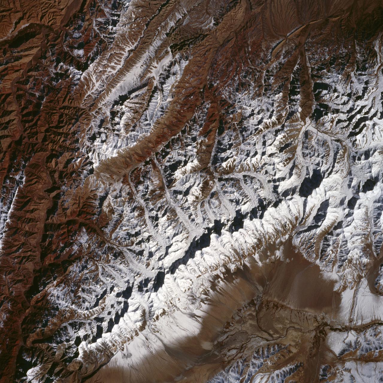 The northwest-southeast trending, snow-covered, linear mountain range is the King Ata Tag Mountain, located in extreme western most China. Highest peaks are just over 20,100 feet above sea level. The town or village of Muji is located in the largest river valley that is south of this range of mountains. This area includes part of the country of Tajikistan. The center point of the photo is approximately 39.30 degrees north and 74.30 degrees easth.