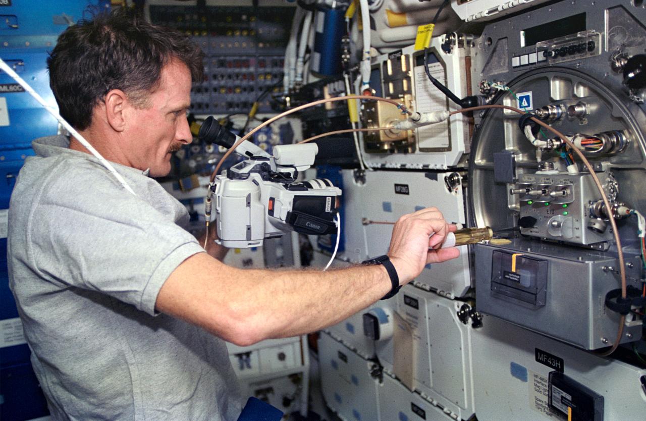 On the Space Shuttle Atlantis' mid-deck, astronaut Joseph R. Tanner, mission specialist, works at area amidst several lockers onboard the Shuttle which support the Protein Crystal Growth (PCG) experiment. This particular section is called the Crystal Observation System, housed in the Thermal Enclosure System (COS/TES). Together with the Vapor Diffusion Apparatus (VDA), housed in a Single Locker Thermal Enclosure (SLTES) which is out of frame, the Cos/TES represents the continuing research into the structures of proteins and other macromolecules such as viruses.
