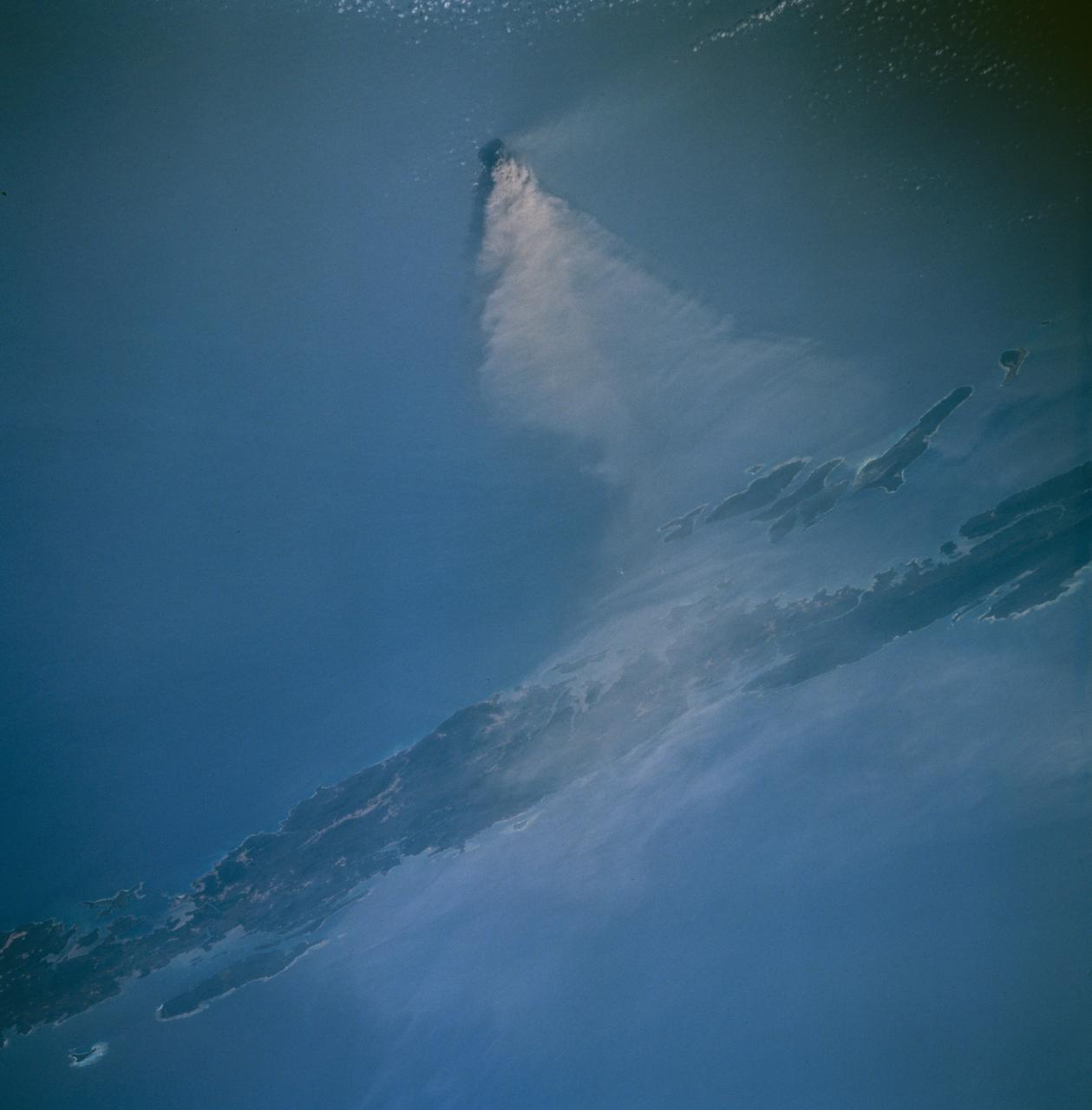 Barren Island, a small volcanic island which is part of the Andaman Island group in the Andaman Sea west of Malaysia, began a new eruptive phase late in 1994. The STS-67 crew noticed the volcanic plume early in their flight, and had several opportunities to document the on-going eruption. This view, taken March 14, 1995, shows a healthy volcanic plume rising several thousand feet into the atmosphere. The main plume drifts westward over Andaman Island, although a smaller plume close to the ground is being dispersed to the south.