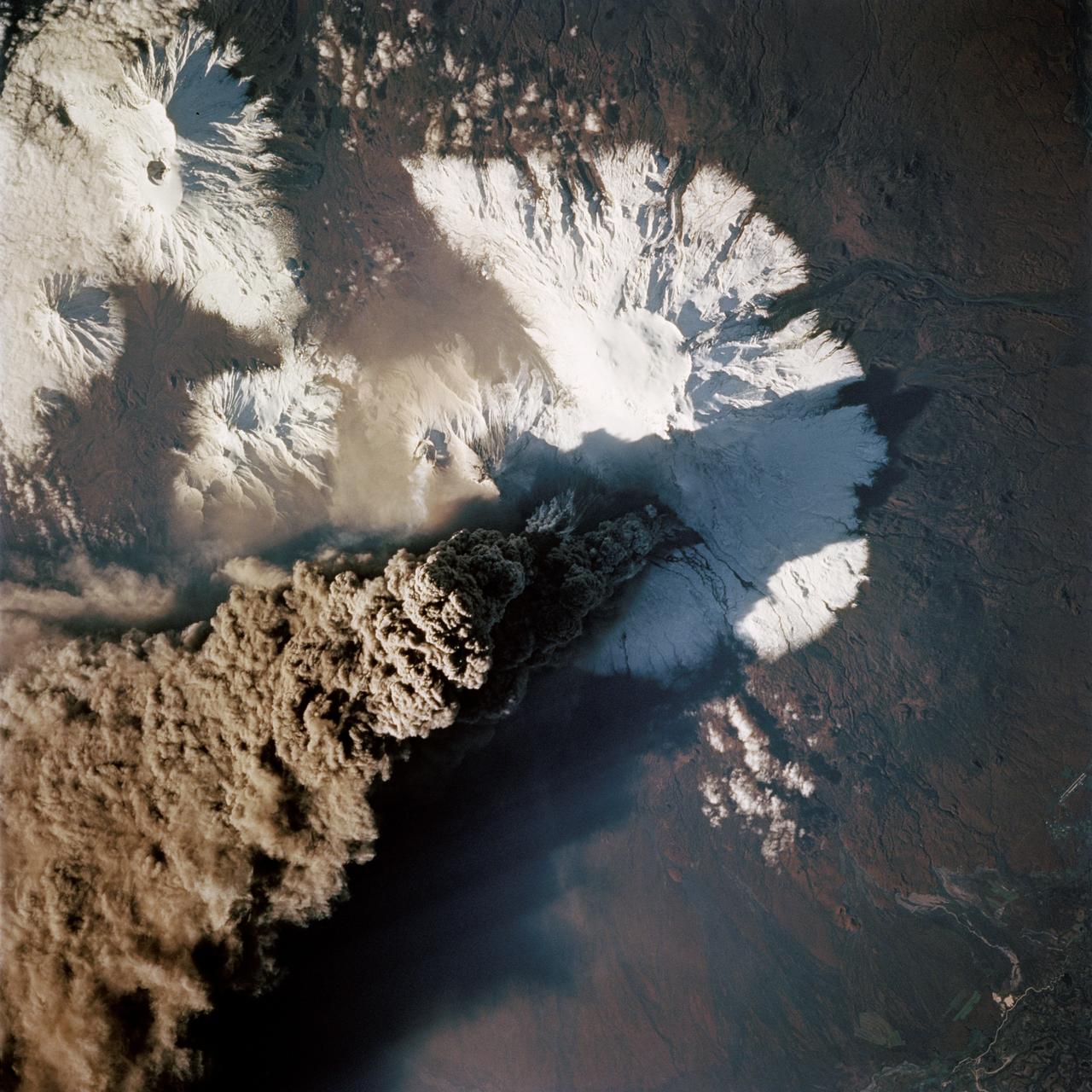 STS068-214-035 (30 September 1994) --- One of the first photos taken by the crewmembers on launch day of the Space Shuttle Endeavour was this 70mm frame of the Kliuchevskoi volcano on the Kamchatka Peninsula in Russia.  The volcano was near its peak at this time.  The large, black eruption plume billows from the summit, as ash is being deposited on the snow-covered region to the east and southeast (north is to upper left).  A small steam plume rises from the peak of Bezymianny just south of Kliuchevskoi (or just right of center).  As various members of the six-person crew were using handheld cameras to record the eruption, hardware in Endeavour's cargo bay was taking radar data of the event in support of the Space Radar Laboratory (SRL-2) project.