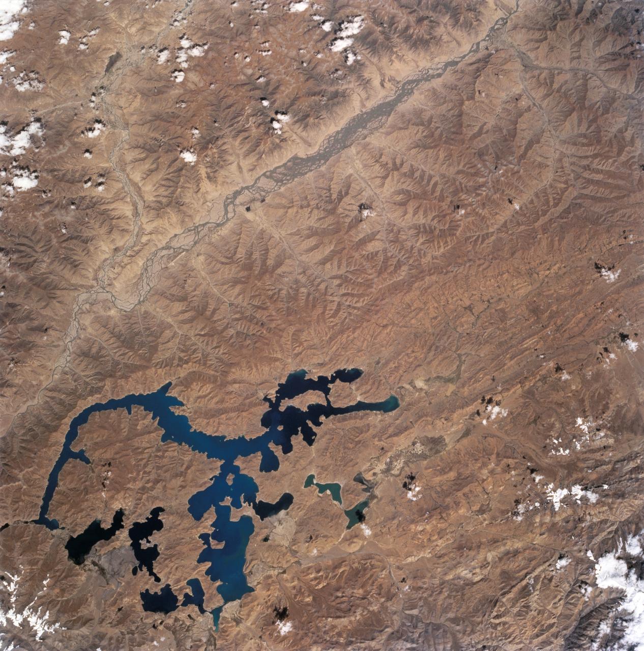 STS068-243-012 (30 September-11 October 1994) --- This nadir view of the southern Tibetan Plateau shows the plateau in late summer without snow. It also shows large, irregular Lake Yamzho Yumco, which has the unusual feature of different water color in different places, the darkest water apparently related to the remotest bays, and the lighter color resulting from sediment flowing into the lake from a stream bottom left. The multiple-channeled upper Brahmaputra River cuts the top left corner of the frame, flowing east (to the top right). The tributary entering the frame near the top left corner is the Lhasa River: Lhasa lies on this river just outside the frame.