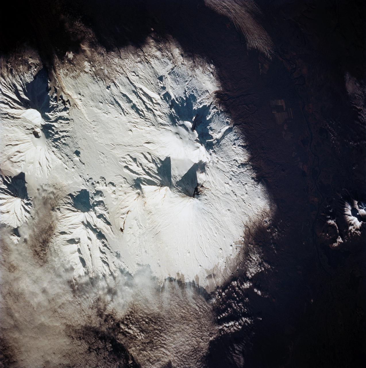 STS068-258-028 (9 October 1994) --- Astronauts aboard the Space Shuttle Endeavour recorded this final 70mm frame of the Kliuchevskoi volcano on the Kamchatka Peninsula in Russia.  The volcano was near its peak on launch day, 10 days earlier, but a snowstorm left very little indication of the major event that had occurred here, except for the ash-covered summit and the large black flow down the northern flank of the mountain.  As various members of the six-person crew were using handheld cameras to record the various stages of the volcano, hardware in Endeavour's cargo bay was taking radar data of the event in support of the Space Radar Laboratory (SRL-2) mission.