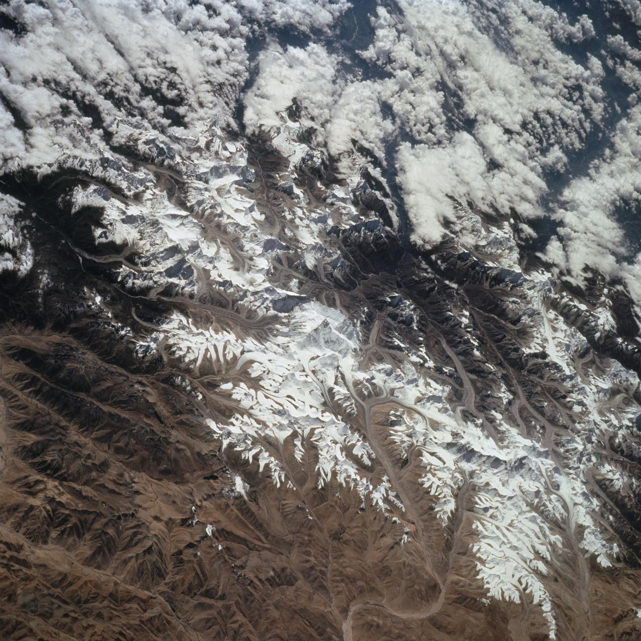 STS068-259-009 (30 September-11 October 1994) --- This south-looking, summer-time view of Mt. Everest (center) - with strong sense of three dimension because of reduced amount of snow - and neighboring peaks of the Himalayas. Clouds cover lower slopes in India.