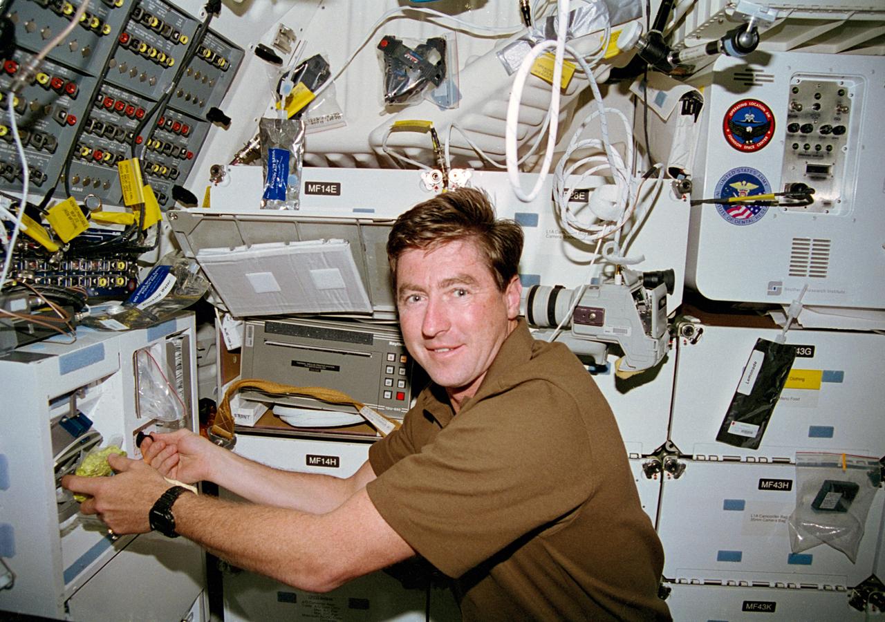 STS070-333-016 (13-22 JULY 1995) --- At the space shuttle Discovery?s galley on the middeck, astronaut Terence T. (Tom) Henricks, mission commander, prepares to rehydrate a package of broccoli au gratin.  A packet of punch and another beverage pouch filled with lemonade can be seen temporarily stowed on locker exteriors nearby.