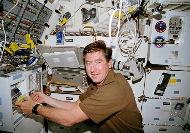 NASA image: Henricks rehydrates a food packet at the shuttle orbiter repackaged galley (SORG)