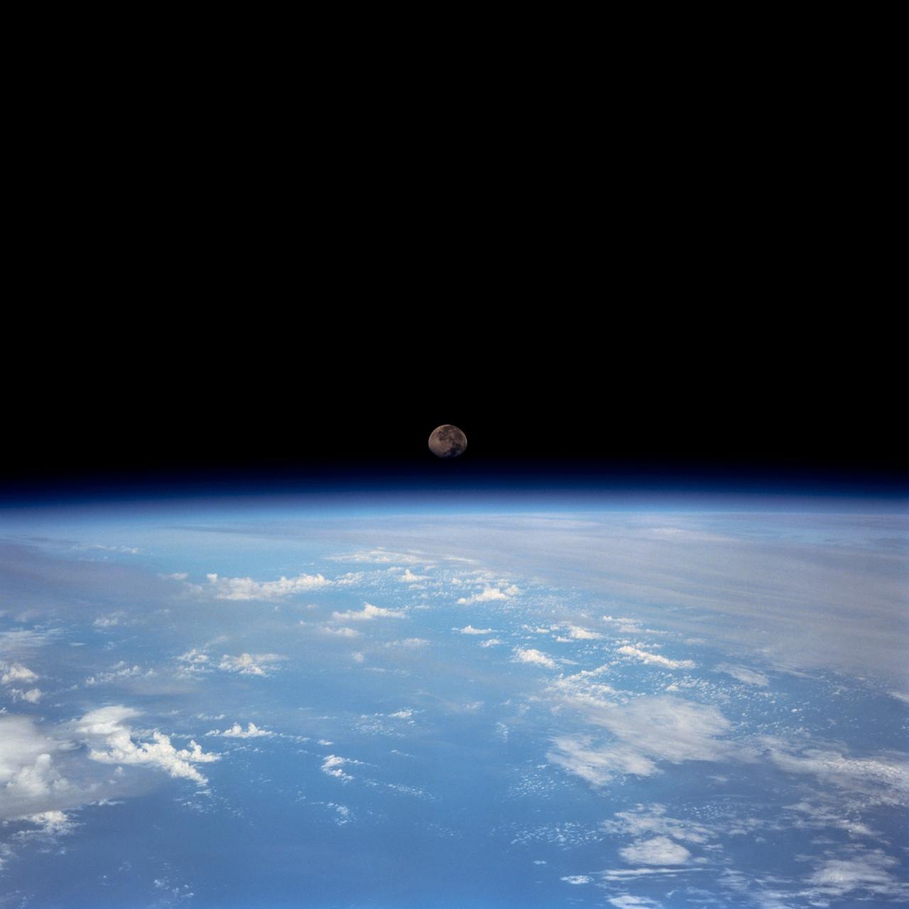 STS070-701-070 (13-22 JULY 1995) --- Dark surfaces of lunar mare can be identified on the ?tiny? Moon in the center of this clear 35mm frame, recorded by crew members aboard the Earth-orbiting Space Shuttle Discovery.  A variety of cloud-types obscure land and water in the scene.  Several tropical storms and tropical depressions were observed by the crew during its nine-day mission.