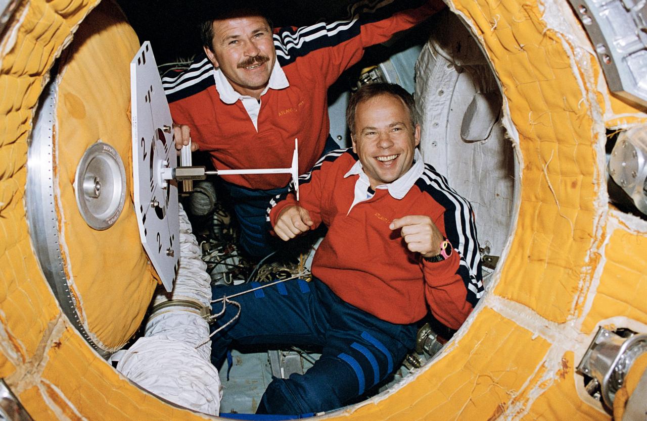 View of the Mir 19 commander Anatoly Solovyev and flight engineer Nikolai Budarin preparing to close the hatch to the docking module which leads to the Mir space station.
