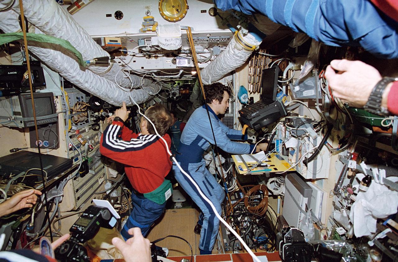 STS071-118-007 (27 June - 7 July 1995) --- Onboard the Russia?s Mir Space Station Mir Base Block, cosmonauts Anatoly Y. Solovyev (left) and Vladimir N. Dezhurov, Mir 19 and 18 commanders, respectively, exchange information about their research tasks.  The two represent a change of guard aboard Mir, as Dezhurov prepares to come back to Earth with the STS-71 crew aboard Space Shuttle Atlantis.  Nikolai M. Budarin and Gennadiy M. Strekalov - cosmonaut/flight engineers making the same exchange -- are out of frame.