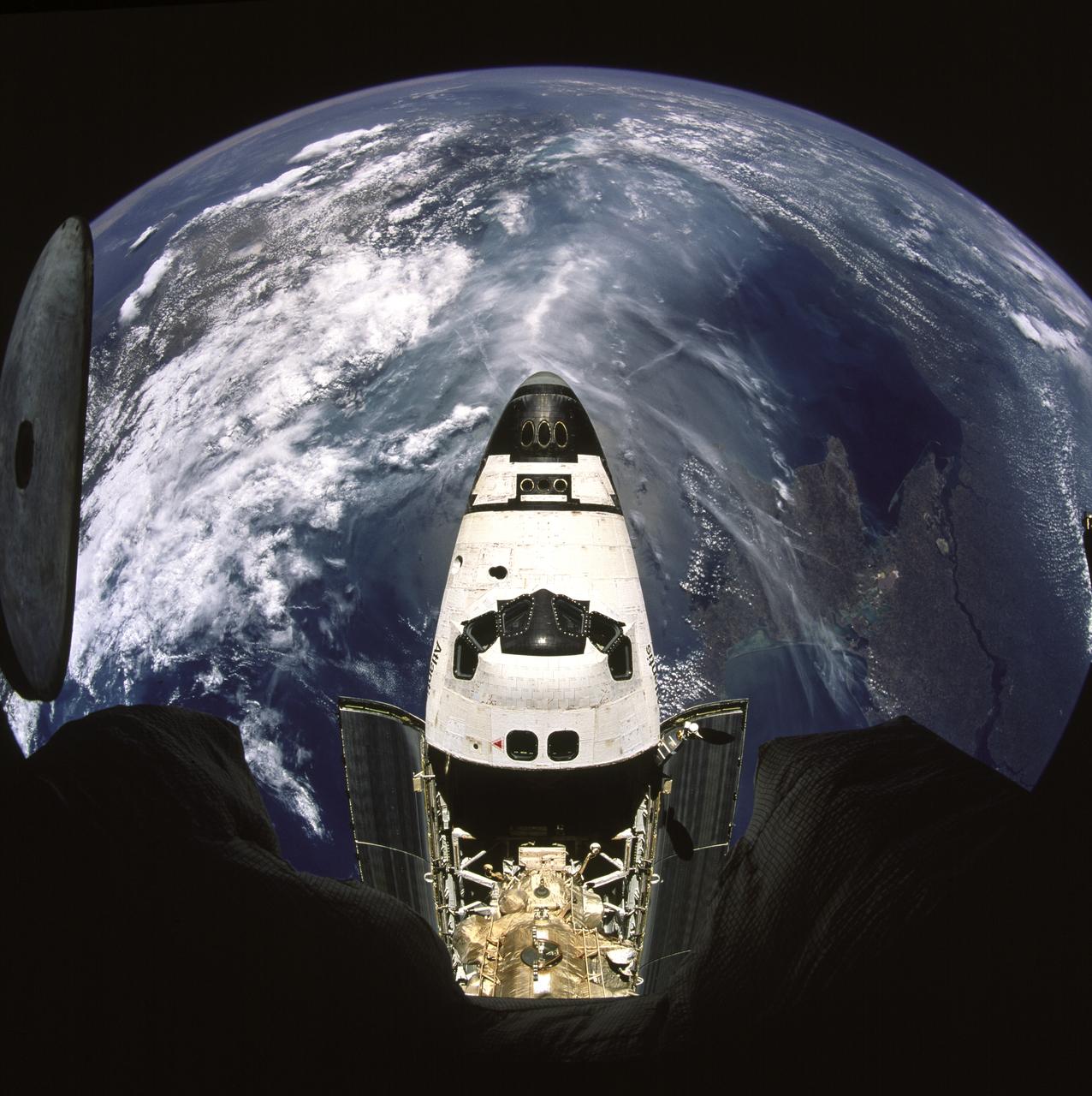 STS071-741-004 (27 June-7 July 1995) --- Docked already with Russia's Mir Space Station and backdropped against a half globe of Earth featuring the Crimean Peninsula, the space shuttle Atlantis is partially visible through a window on the Kvant 2 Module.  A 70mm camera, carried into space by the STS-71 crew aboard the space shuttle Atlantis, was used to expose the image.  The crew cabin and forward cargo bay of Atlantis are most prominent.  Below center can be seen the Androgynous Peripheral Docking System (APDS) and the Kristall Module on Mir.  The APDS is connected to a port in a tunnel leading to the Spacelab Science Module in Atlantis' cargo bay.  The linkup enabled the seven STS-71 crew members to visit Mir and it allowed the three Mir-18 crew members, in space since March of this year, access to Spacelab.  That module was quite busy with tests and data collection involving the three, Mir-18 crew, until Atlantis brought them home on July 7, 1995.  The Black Sea lies directly beneath Atlantis, with Ukraine's diamond-shaped Crimean Peninsula immediately to the right of the cockpit.  The wide lower course of the Dnepr River can be seen entering the Black Sea at far right.  The coast of Romania and Bulgaria lies at a point where the cloud begins at top right.  The peninsula of Asia Minor lies across the left of the view, mostly under cloud cover.  The Mediterranean Sea is the cloud-free, blue mass beyond.  Still further, at about 1,300 miles distance, the north edge of Africa is stretched out as a line across the horizon with its characteristic sandy color.  The nose of Atlantis points southwest toward the only outlet of the Black Sea known as the Bosporus.