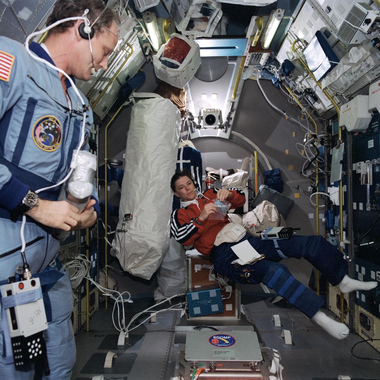 STS071-758-009 (27 June - 7 July 1995) --- Astronaut Bonnie J. Dunbar, mission specialist, floats about in the Spacelab Science Module as astronaut Norman E. Thagard looks on.  Thagard, Mir-18 guest cosmonaut researcher, had completed four months in space aboard Russia's Mir Space Station.  When this photograph was taken he was undergoing a battery of tests and data collection exercises on Spacelab, onboard the Space Shuttle Atlantis.  Dunbar had served as his Mir-18 backup, during a year's training in Russia.