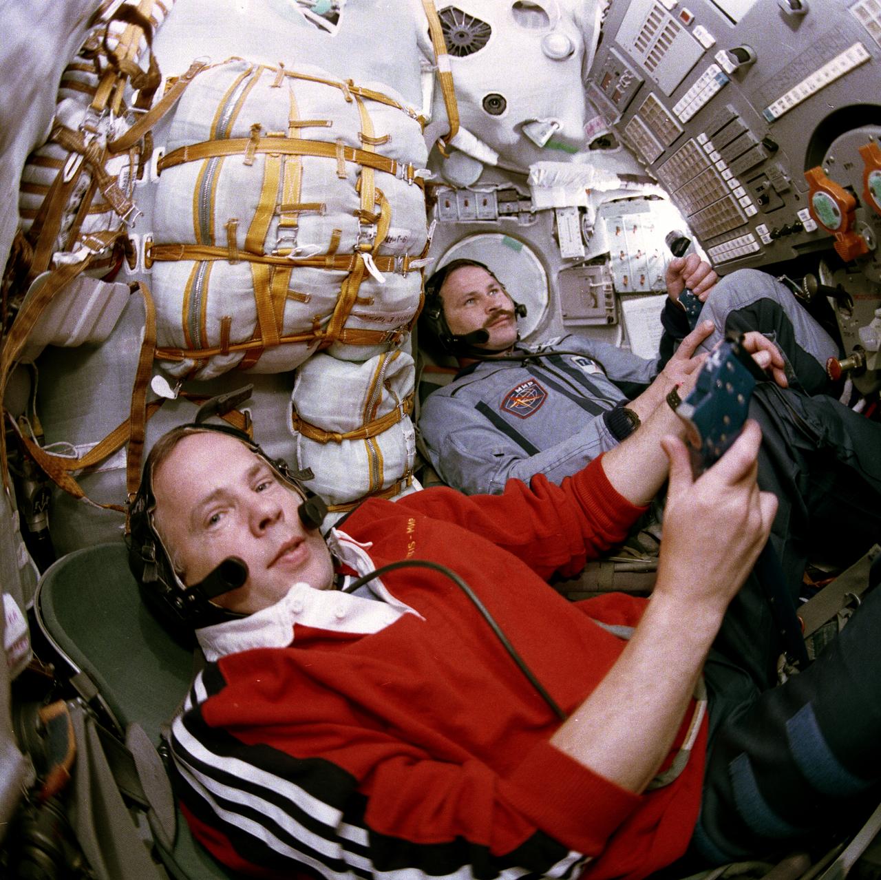 STS071-763-007 (27 June-7 July 1995) --- Onboard the docked Soyuz spacecraft, cosmonauts Anatoly Y. Solovyev (left) and Nikolai M. Budarin, Mir 19 commander and flight engineer, respectively, conduct a checkout of communications systems.  The two represent the new in a change of guard aboard Russia's Mir Space Station, as Mir-18 astronaut Norman E. Thagard and two Mir-18 cosmonauts prepare to come back to Earth with the STS-71 crew aboard the space shuttle Atlantis.  Later in the joint mission, Solovyev and Budarin backed the Soyuz spacecraft away from the Mir/Atlantis tandem to allow for the space shuttle Atlantis to undock with its crew of six astronauts and two cosmonauts aboard.