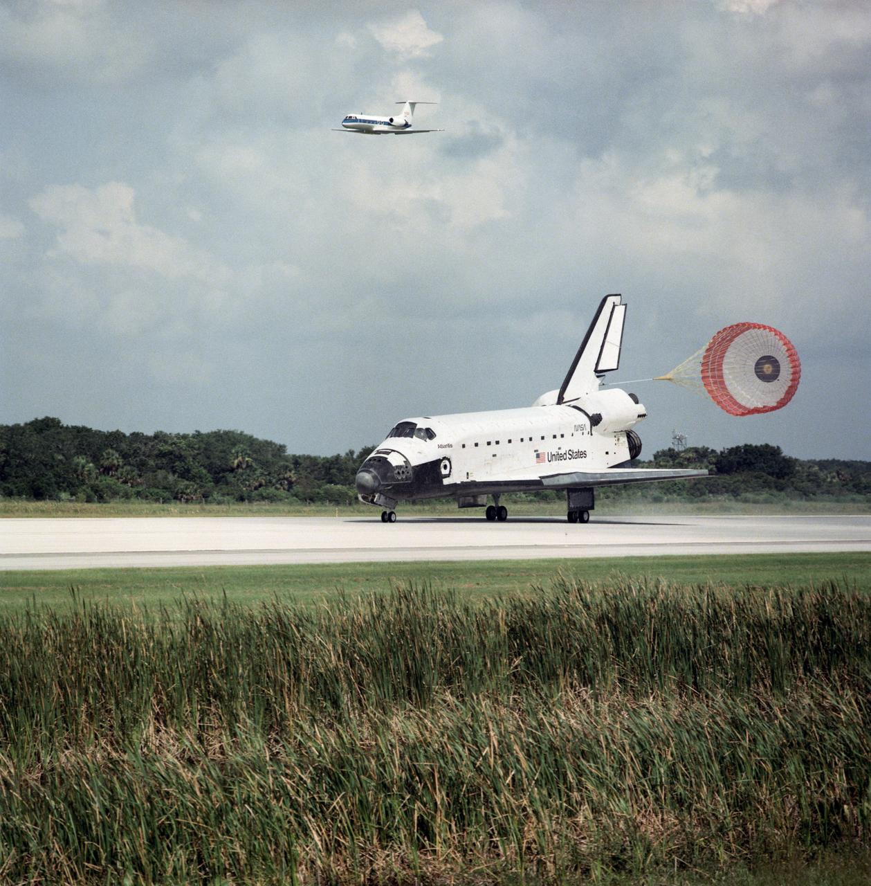 STS071-S-070 (7 July 1995) --- The drag chute of the Space Shuttle Atlantis is deployed as the spacecraft touches down on Runway 33 at the Kennedy Space Center's (KSC) Shuttle landing facility.  The Shuttle Training Aircraft (STA) piloted by astronaut Robert D. Cabana, is visible in upper left.  The landing completed an historic mission in space involving a linkup with Russia?s Mir Space Station and the Space Shuttle Atlantis, a total of six astronauts and four cosmonauts.  Onboard for the landing were six NASA astronauts and two cosmonauts.  Touchdown occurred at 10:55 a.m. (EDT), July 7, 1995.