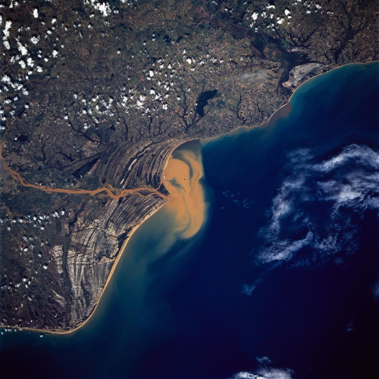STS072-738-019 (11-20 Jan. 1996) --- The Delta of the Paraiba do Sul River, northeast of Rio de Janeiro, Brazil, stands out in this 70mm frame exposed from the Earth-orbiting Space Shuttle Endeavour.  The brown color of the river water and offshore sediment plume show that the river is in flood stage.  This delta attracts much attention from orbit because of its prominent beach ridges either side of the river mouth.  River sediment from inland supplies the material which is redistributed by coastal currents to form the parallel beach ridges.  The lower 20 miles of the river appear in this scene.  The river flows into the Atlantic in an easterly direction.