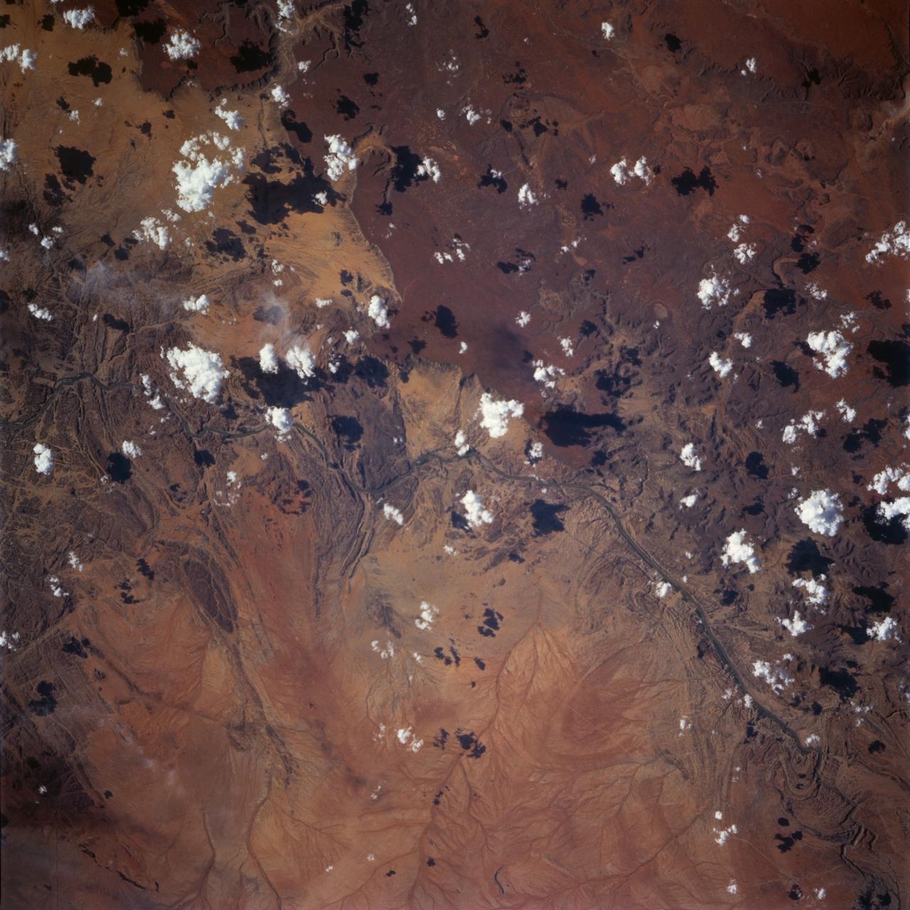 STS072-738-036 (11-20 Jan. 1996) --- The astronauts used a 70mm handheld camera to expose this frame of the west-flowing Orange River, which constitutes the international boundary between Namibia and the Republic of South Africa.  The railroad and highway connecting the two countries is seen as a ribbon crossing the corner of the view.  The broad color difference between strong browns/reds in the northern half of the view and lighter yellows in the southern corresponds to two land surfaces.  The darker is a higher, flat land surface developed on horizontal Nama Sandstone’s, with rock surfaces widely coated with a dark manganese stain, typical of desert regions.  This region is known as Namaqualand and borders the Namib Desert.  Where rivers have cut down into this surface, the lighter underlying rock and soil colors show up.