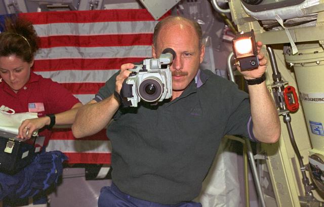 STS073-230-014 (20 October - 5 November 1995) --- Astronaut Kenneth D. Bowersox, STS-73 mission commander, uses a camcorder to record United States Microgravity Laboratory 2 (USML-2) activities onboard the Space Shuttle Columbia.  Nearby, astronaut Kathryn C. Thornton, payload commander, prepares to open a supply chest to support one of many science experiments conducted by the seven-member crew during the 16-day USML-2 flight.