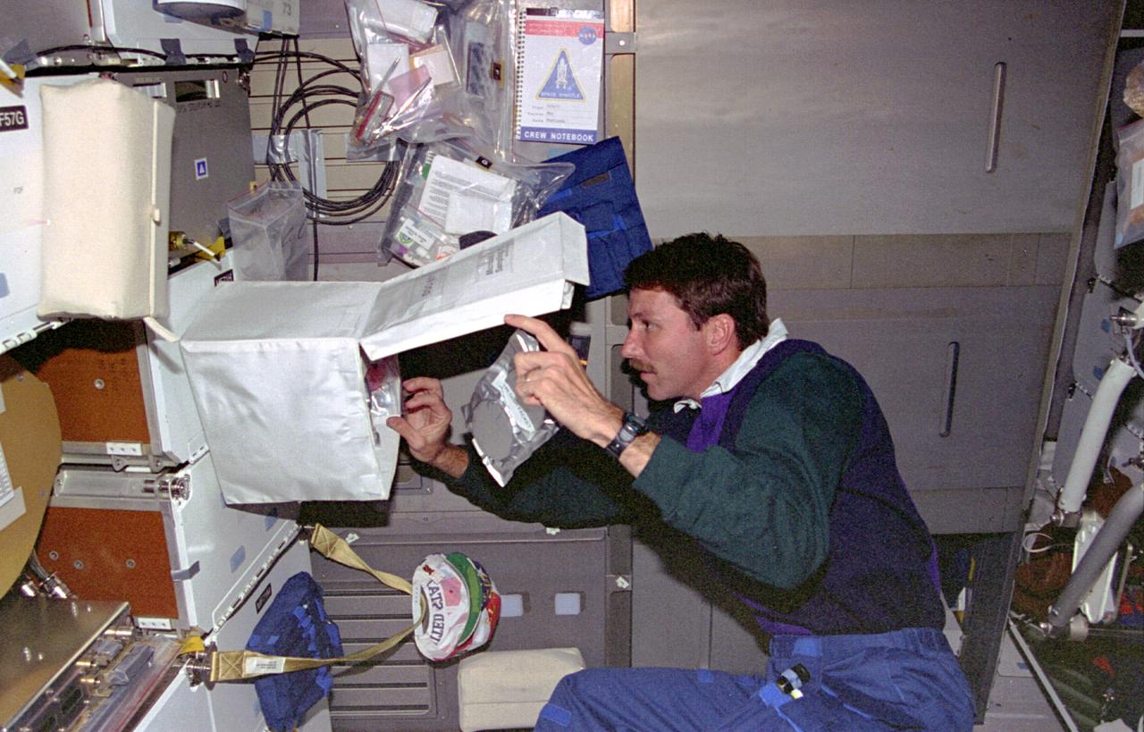 STS073-352-008 (20 October - 5 November 1995) --- On the middeck of the Earth-orbiting Space Shuttle Columbia, astronaut Kent V. Rominger, STS-73 pilot, retrieves gear necessary for sampling of the air. In addition to his pilot duties and the performance of tasks in support of the U.S. Microgravity Laboratory (USML-2) mission, Rominger and other crew members pitched in with housekeeping chores as part of their 16-days of Earth-orbit activity.