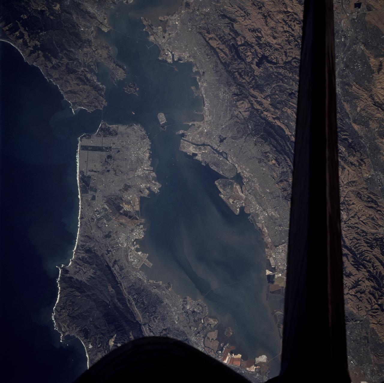 STS073-706-012 (22 October 1995) --- Each of the great bridges spanning San Francisco Bay are captured in this near-nadir photo of the San Francisco and Oakland, California, areas.  Starting from the south (left in this photo), Dumbarton, San Mateo, Bay, Golden Gate, and San Rafael bridges are seen.  Ribbons of run-off induced sediments color the bay, and multi-colored salt-production pens line the southernmost shore.