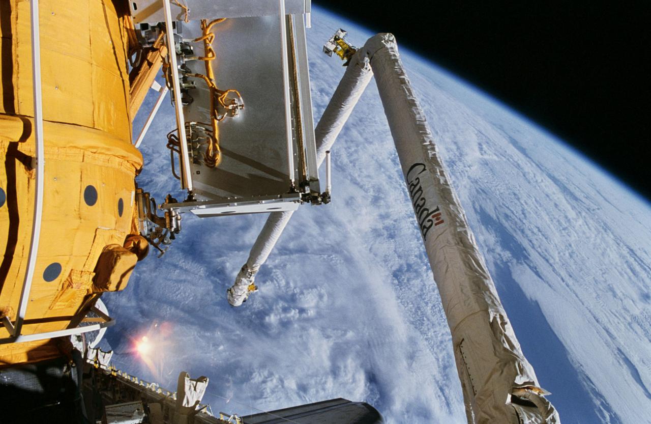 STS074-321-027 (12-20 Nov 1995) --- One of the STS-74 crew members aimed a 35mm camera through aft flight deck windows of the Space Shuttle Atlantis to record this scene of the Remote Manipulator System (RMS) arm and the new Russian Docking Module (DM), backdropped against storm clouds on Earth.  With five NASA astronauts aboard, the flight of Atlantis began with a November 12, 1995, launch from Kennedy Space Center (KSC) and ended with landing there on November 20, 1995.  The STS-74 crew members were astronauts Kenneth D. Cameron, mission commander; James D. Halsell Jr., pilot; William S. McArthur Jr., Jerry L. Ross and Canadian astronaut Chris A. Hadfield, all mission specialists.  On November 15, 1995, the Space Shuttle Atlantis docked with the Mir Space Station, on which the STS-74 astronauts joined the Mir-20 crew.  The Mir-20 crew is composed of cosmonauts Yuriy P. Gidzenko, commander; and Sergei V. Avdeyev, flight engineer; along with the European Space Agency?s (ESA) Thomas Reiter, cosmonaut researcher.  Joint activities on the Mir Space Station and the Space Shuttle Atlantis ended November 18, 1995, when the two spacecraft separated.