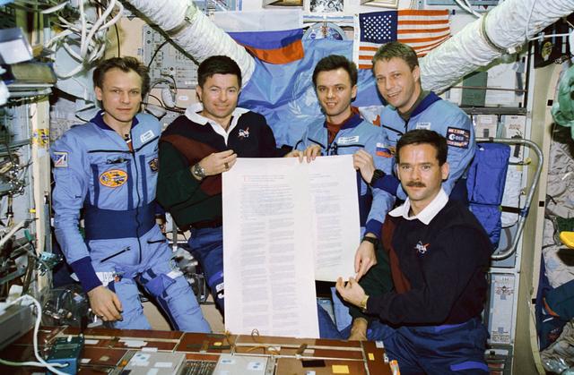 NASA image: STS-74 and Mir 20 crewmembers with U.N. scroll