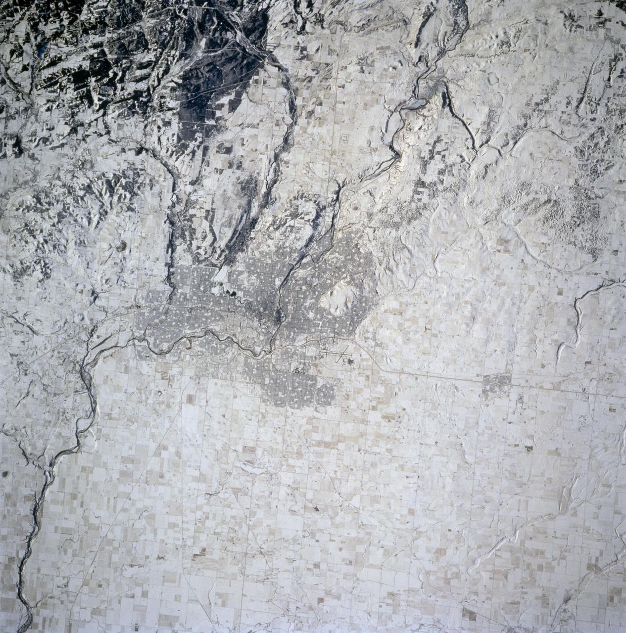 STS074-714-002 (12-20 Nov 1995) --- The late fall season is tell-tale in this nadir view of Calgary, Alberta, Canada as photographed from the Space Shuttle Atlantis.  The ground cover makes it easier to identify geographic and man-made features in the scene.  A gateway to the Canadian Rocky Mountains (lower left corner of the photo), Calgary, with a 1994 population listed at 710,677 is noted for its livestock and summer rodeos.  It is located on the Bow River, easily traced as it meanders through the city.  The Calgary International Airport is easily seen north east of the city.