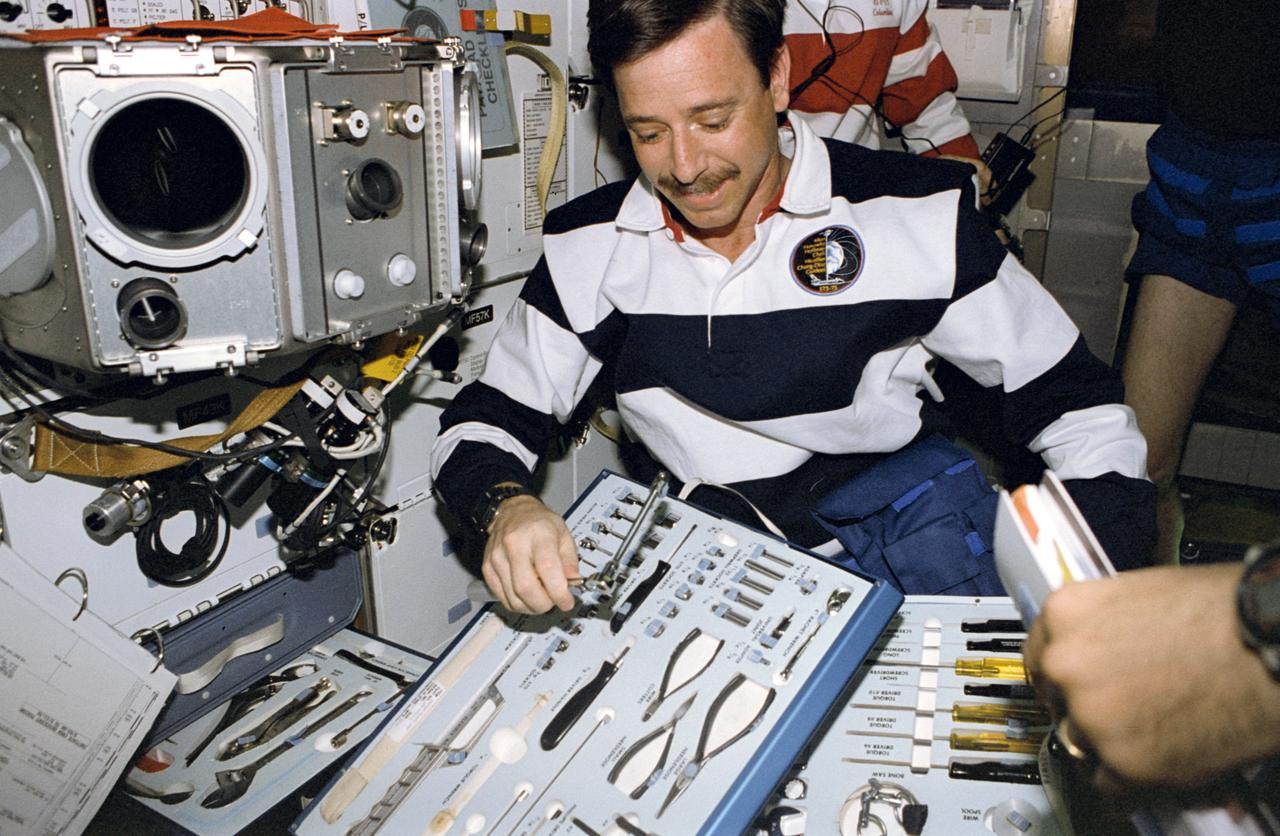 STS075-333-032 (22 Feb.- 9 March 1996) --- Astronaut Scott J. Horowitz, pilot, looks over tools he may use to perform an Inflight Maintenance (IFM) chore on the mid deck of the Earth-orbiting space shuttle Columbia. The glovebox facility is at upper left. Horowitz joined four other astronauts and an international payload specialist for 16 days of scientific research in Earth-orbit.