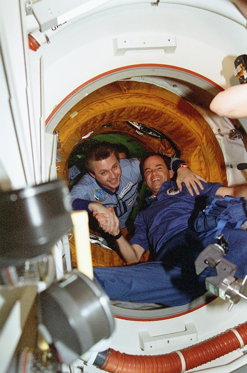 STS076-344-013 (24 March 1996)--- Continuing an in-space tradition, astronaut Kevin P. Chilton (right), mission commander, shakes hands with cosmonaut Yury I. Onufrienko, Mir-21 commander, in the tunnel connecting the Space Shuttle Atlantis and Russia's Mir Space Station.  A short time earlier two crews successfully pulled off the third hard-docking of their respective spacecraft.  The image was made with a 35mm camera.