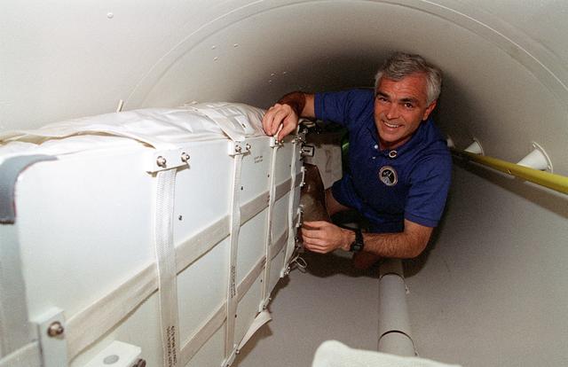 NASA image: Astronauts move through narrow space in tunnel adapter filled with transfer bag