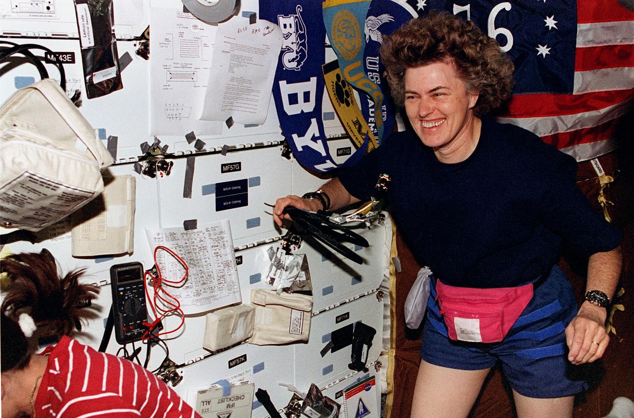 STS076-370-005 (22-31 March 1996) --- Astronaut Shannon W. Lucid, mission specialist and future cosmonaut guest researcher, appears to enjoy her last hours aboard the Space Shuttle Atlantis before becoming a crew member supporting the Mir-21 mission aboard the Russia's Mir Space Station.  Astronaut Linda M. Godwin is partially visible at left as she works at one of the mid deck lockers.