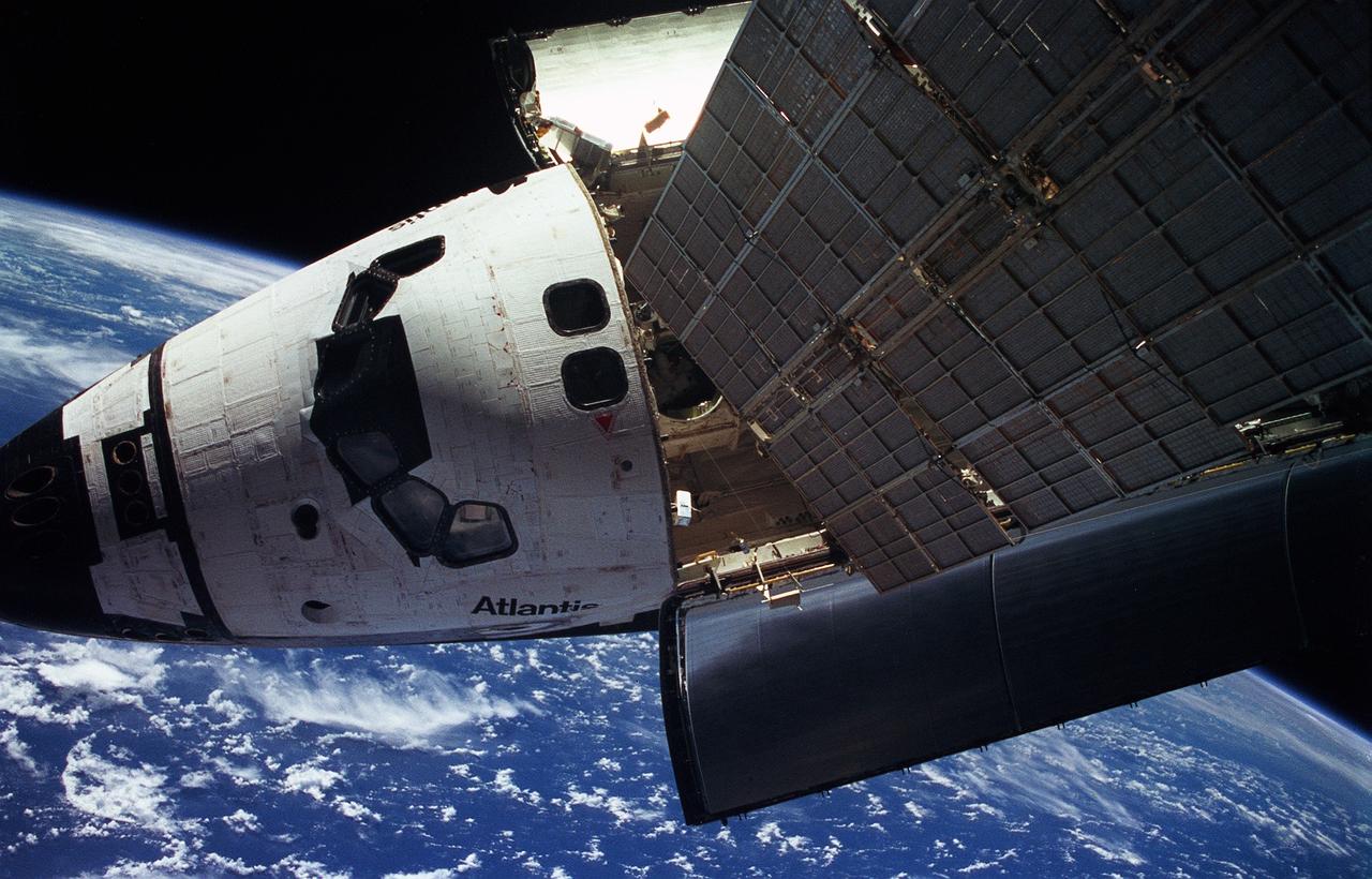 STS076-401-009 (22 - 31 March 1996) --- This photo of the crew cabin of the Space Shuttle Atlantis was taken from Russia's Mir Space Station as the two spacecraft jointly orbited Earth in late March 1996.  Earth's horizon and clouds over the Indian Ocean form part of the backdrop for the scene.  The large rectangular object in the immediate foreground is one of the solar array panels for Mir.  The two spacecraft were in the midst their third link-up in Earth-orbit.  With the subsequent delivery of astronaut Shannon W. Lucid to the Mir, the Mir-21 crew grew from two to three, as the mission specialist temporarily became a cosmonaut guest researcher.  She is to spend approximately 140 days on Mir before returning to Earth.