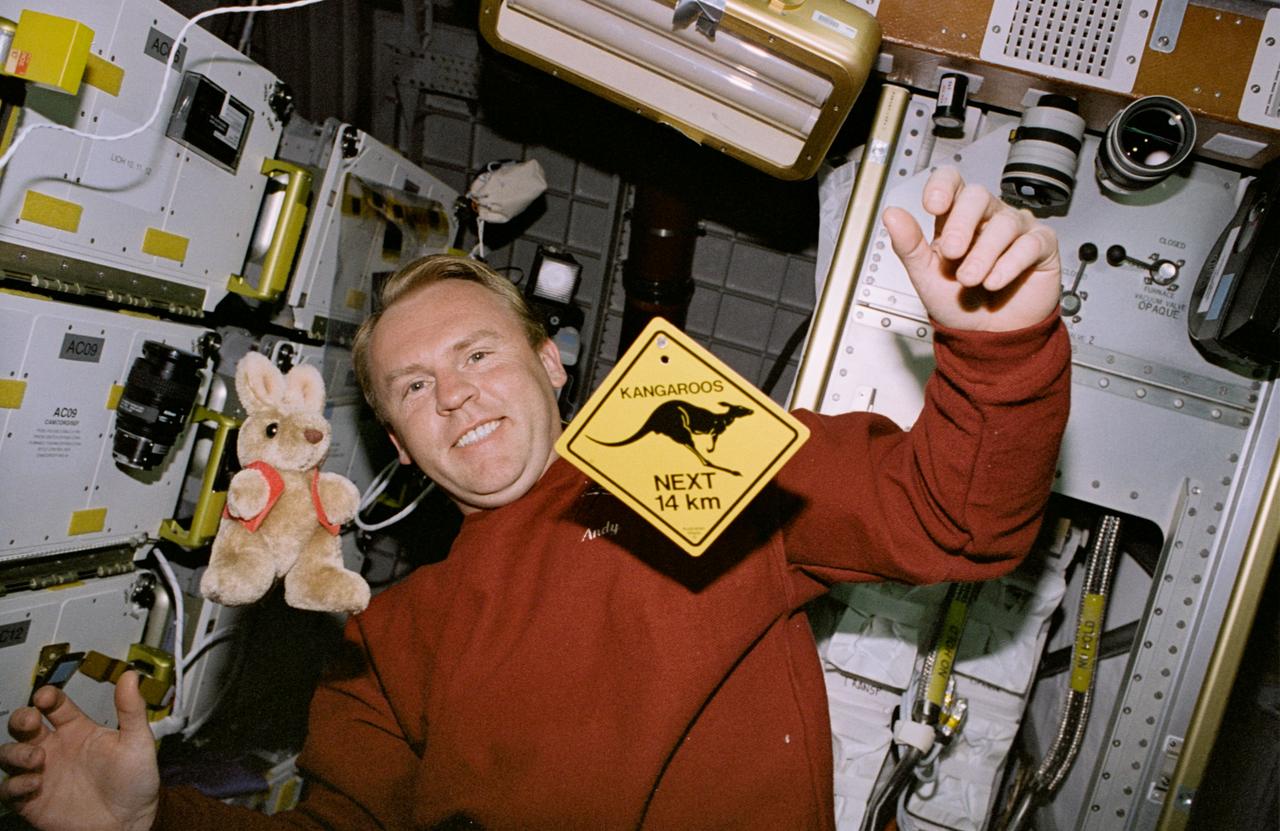 STS077-368-026 (19-29 May 1996) --- On his off-duty time, Australian-native Andrew S. W. Thomas, mission specialist, has a little fun with Australian mementos in the Spacehab Module onboard the Space Shuttle Endeavour. Floating in the foreground are a stuffed toy kangaroo and a miniaturized typical highway warning sign about the plentiful four-legged Australian resident. Astronaut Thomas and five other crew members went on to spend almost ten-days aboard Endeavour in support of the Spacehab 4 mission and a number of other payloads.
