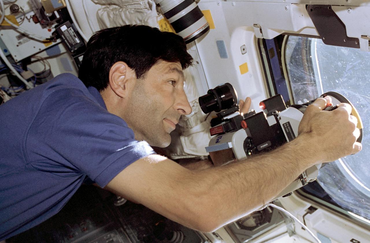 STS077-372-020 (19-29 May 1996) --- On the Space Shuttle Endeavour?s aft flight deck, astronaut Mario Runco, Jr., mission specialist, uses a large format camera during station keeping operations with the Passive Aerodynamically Stabilized Magnetically Damped Satellite (PAMS)/Satellite Test Unit (STU).  During the flight, the six-member crew was involved in deployment and rendezvous operations with the Spartan 207/Inflatable Antenna Experiment (IAE) as well as the PAMS/STU.