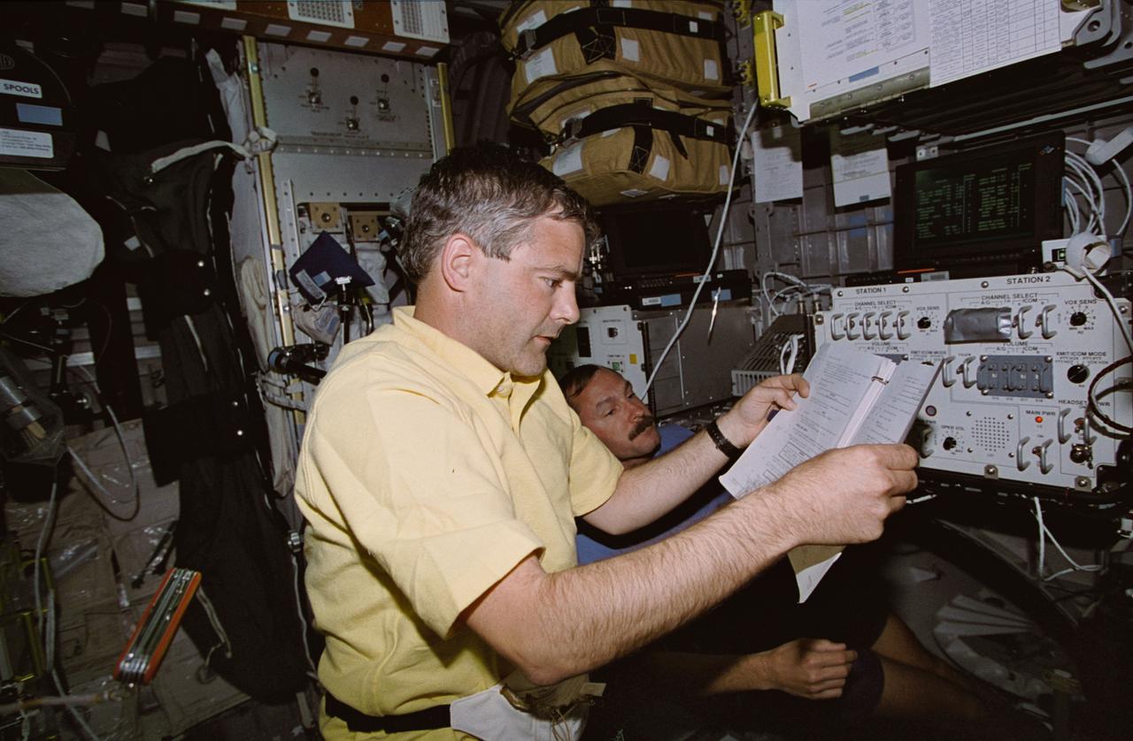 STS077-392-007 (19-29 May 1996) --- Inside the Spacehab Module onboard the Earth-orbiting Space Shuttle Endeavour, Canadian astronaut Marc Garneau, mission specialist, joins astronaut Curtis L. Brown, Jr., pilot, in checking out the audio control system for Spacehab. The two joined four other NASA astronauts for nine days of research and experimentation in Earth-orbit.