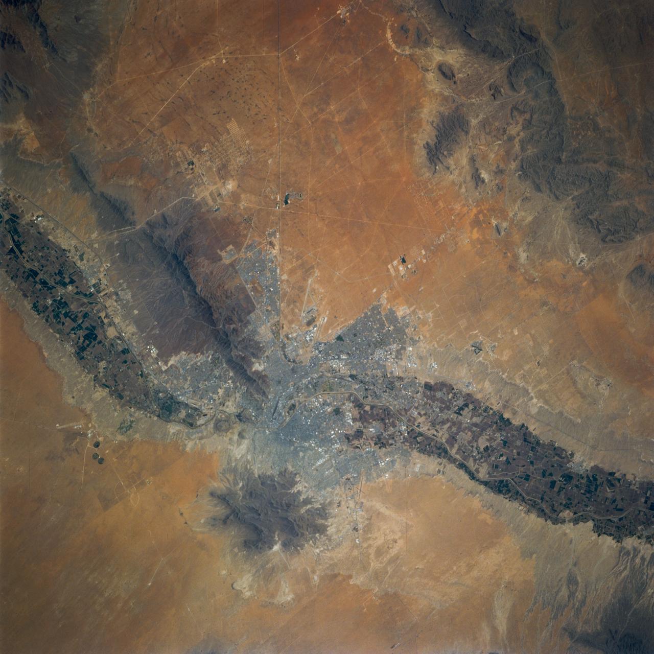 STS077-707-097 (19-29 May 1996) --- This 70mm photograph shows the contrasts between the Chihuahua Desert and the irrigated bottomlands of the Rio Grande. The twin cities of Juarez, Mexico, and El Paso, Texas, on opposite sides of the border are in the center of the frame. The area was first colonized in 1598 making it one of the oldest settlements of Europeans on the North American continent. The name of El Paso derives from the Spanish ?El Paso del Norte.? The City of El Paso became a United States city in 1873. The pass allows passage through the Rocky Mountains in this region. The extension of the Rockies to the northwest of El Paso is known as the Franklin Mountains. Juarez now has over a million people and El Paso has around 400,000. The economy is driven by the maquiladora industries. Fort Bliss on the United States side is a major employer also. Fort Bliss is the wedge shaped feature in El Paso. The post was first established in 1849 for protection from the Comanches and the last horse Calvary unit was disbanded in 1943.