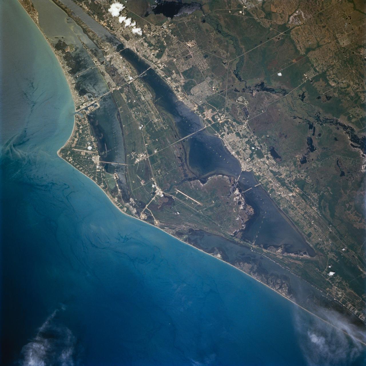 STS077-713-010 (19-29 May 1996) --- Like a number of Shuttle flight crews that preceded them, the members of the crew aboard the Space Shuttle Endeavour made eastern Florida one of their photographic targets.  Both launch and landing sites are visible in the image.  The Space Shuttle runway is at center.  Above and to the left, along the coast, are the two main launch pads for the STS program.  A road connecting the launch pads to the Vehicle Assembly Building (VAB) can be easily delineated.  The Visitors Center for Kennedy Space Center (KSC) is above and to the right of the VAB.  Above the Visitors Center is the NASA Causeway.  Small white dots from the lower left and extending to the right corner outline the Intracoastal Waterway.  The city of Cocoa Beach extends along the coast at the upper right.  A small boat can be seen as a white dot to the right of Cape Canaveral with a distinctive ?V? shaped wake trailing behind.