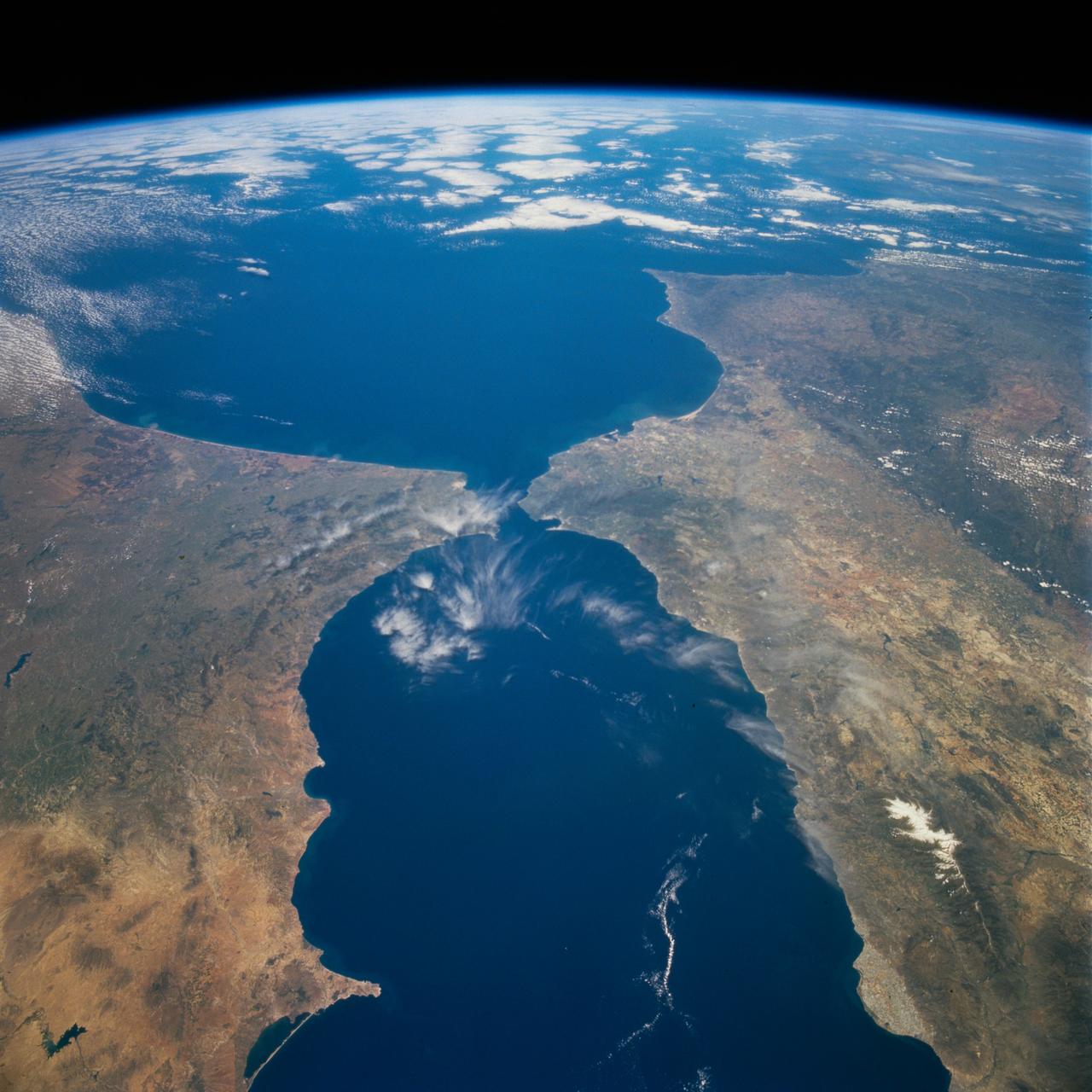STS077-718-088 (19-29 May 1996) --- A popular photographic target of Space Shuttle astronauts has always been the Strait of Gibraltar seen at center in this wide photograph, shot from the Space Shuttle Endeavour. Spain is to the north (right) and Morocco to the south. The strait is 36 miles (58 kilometers) long and narrows to 8 miles (13 kilometers) at it’s most narrow point. The winds in the strait are either easterly or westerly. The British colony of Gibraltar is the semi-circular feature north of the strait. Gibraltar is considered to be one of the Pillars of Hercules. The white colored area to the southeast of Gibraltar on the Moroccan coast is the city of Tanger (Tangier). The snow covered mountains in Spain are the Sistemas Penibeticos.