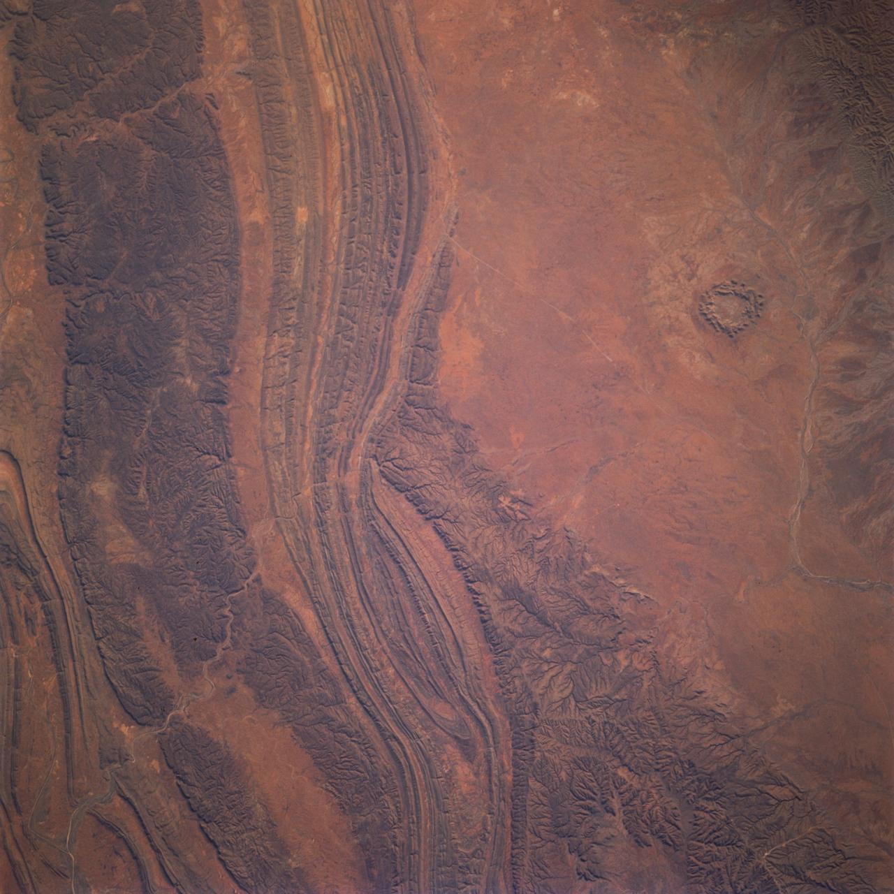 STS077-737-096 (19-29 May 1996) --- The Palmer River emerging from the left corner of the photograph separates the Gardener Range to the right from the James Ranges on the left.  To the bottom and off the photograph is the MacDonnell Ranges.  The circular feature at bottom right is a highly eroded impact crater located on Missionary Plain.  Gosses Bluff is a complex crater about 22 kilometers in diameter and is estimated to be about 142 million years old.