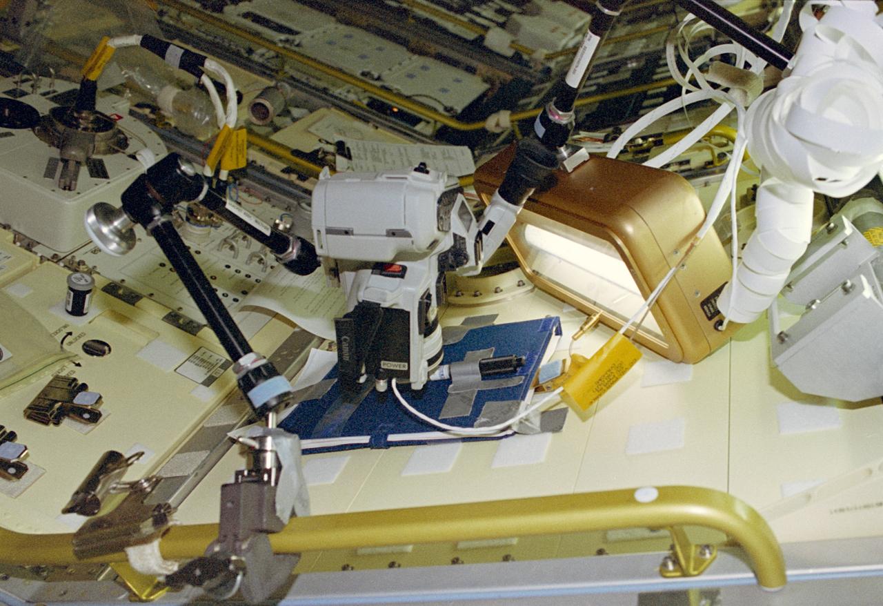 Video camcorder up close to a clyinder attached to a Spacelab locker.