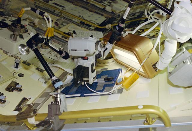 NASA image: Video camcorder up close to a cylinder attached to a Spacelab locker