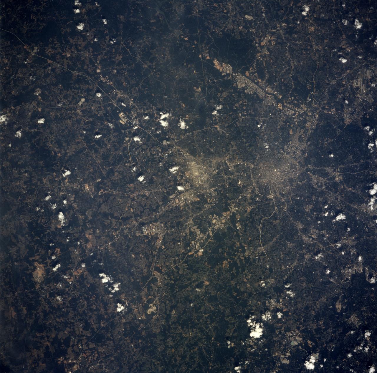 STS078-751-076 (20 June-7 July 1996) --- Metropolitan Atlanta, Georgia, host area for 1996 Summer Olympics was captured on film by one of the crew members using a 70mm handheld camera. Hartsfield Atlanta International Airport is visible to the south of Atlanta, near the center of the photograph. Dobbins Air Force Base and a portion of the city of Marietta can also be seen to the north of Atlanta in the upper left hand corner. The complex system of transportation routes and interstate highways is seen surrounding and traversing Atlanta. The white dot near the center of the city is the Georgia Dome, a major sports and entertainment complex in downtown Atlanta. Atlanta is the cultural, industrial, transportation, financial, and commercial center of the South. It has one of the busiest air traffic hubs in the United States. A major aircraft assembly plant is located north of Atlanta in Marietta. The Stone Mountain Memorial, with its enormous relief carvings of Confederate figures, is located east of Atlanta and is visible on the photograph.