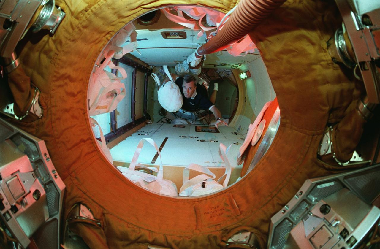 STS079-335-001 (16-26 Sept. 1996) --- Astronaut Terrence W. Wilcutt traverses into Russia's Mir Space Station Kristall Module toting a water bag from the Space Shuttle Atlantis to be used on Mir. This photograph is one of fifteen 35mm frames (along with four 70mm frames) of still photography documenting the activities of NASA's STS-79 mission, which began with a Sept. 16, 1996, liftoff from Launch Pad 39A the Kennedy Space Center (KSC) and ended with a landing at KSC on September 26, 1996.  Onboard for the launch were astronauts William F. Readdy, commander; Wilcutt, pilot; John E. Blaha, Jerome (Jay) Apt, Thomas D. Akers and Carl E. Walz, all mission specialists.  On flight day 4, the crew docked with Mir.  Shannon W. Lucid, who had spent six months aboard Mir, switched cosmonaut guest researcher roles with Blaha.  The latter joined fellow Mir-22 crewmembers Valeri G. Korzun, commander, and Aleksandr Y. Kaleri, flight engineer.