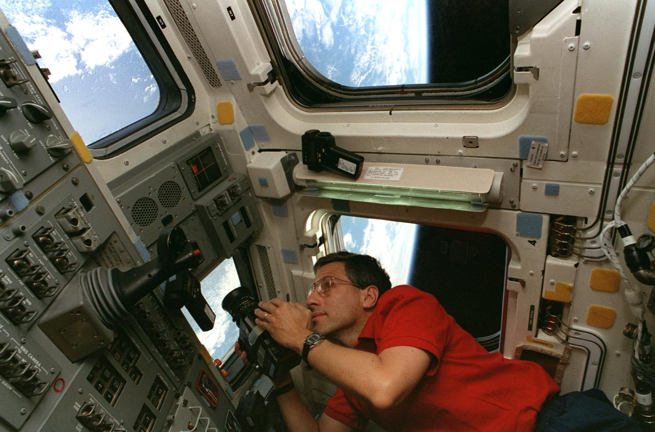 STS079-341-036 (16-26 Sept. 1996) --- Following the space shuttle Atlantis' separation from the Russian Mir Space Station, astronaut Jerome (Jay) Apt, mission specialist, eyeballs a photographic target on Earth prior to capturing it on film with a handheld 70mm camera from the aft flight deck. Scientists at the Johnson Space Center (JSC), who helped to plan the various target sites, will later analyze the film in their Houston laboratories.