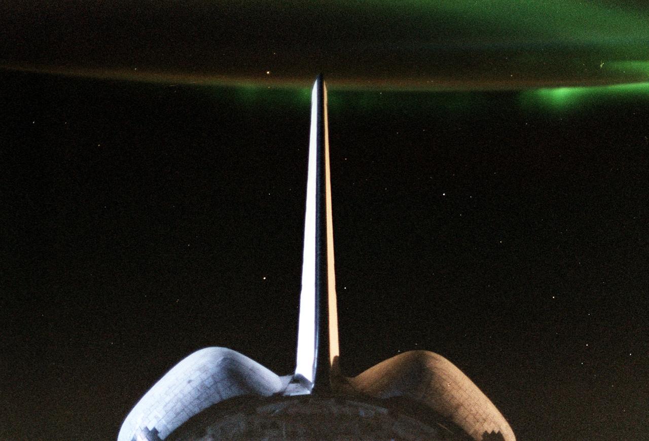 STS079-379-022 (16-26 Sept. 1996) --- If this moonlit picture is held with the Space Shuttle Atlantis' Orbital Maneuvering System (OMS) pods at top, a greenish aurora appears at left edge. Thanks to a time exposure on a 35mm camera, a crew member was able to capture the phenomenon visually experienced frequently by Shuttle crews. Several stars can be seen in the picture. Many of them appear closer to the camera than Earth because they are seen through the thin line of atmosphere above Earth's horizon.