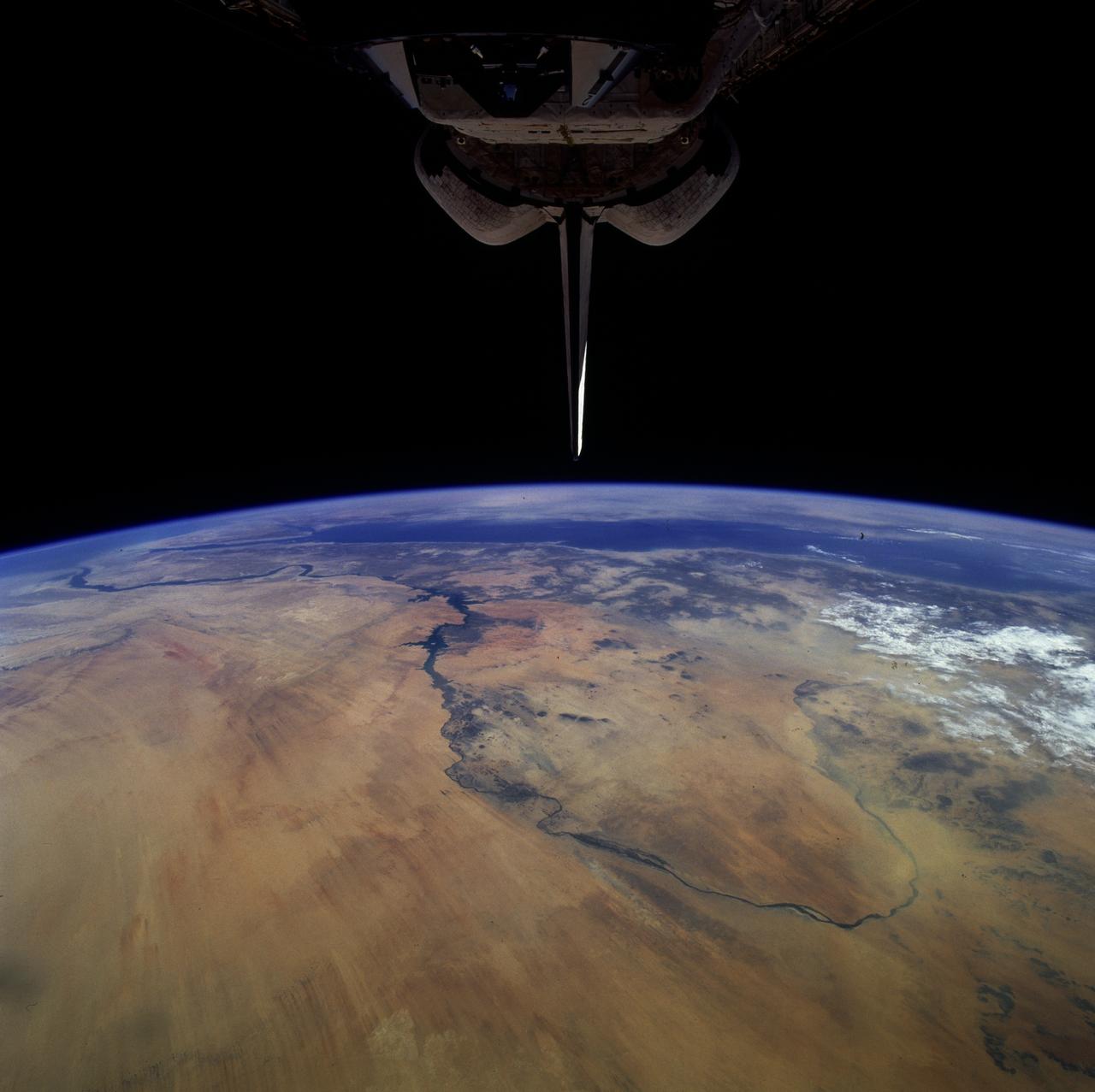 STS079-808-008 (16-26 Sept. 1996) --- In this 70mm frame from the space shuttle Atlantis, the Nile River wanders through the eastern Sahara Desert of Sudan and Egypt. In the foreground is a great bend of the Nile from north to south past the Fourth Cataract at Merowe (an ancient Sudanese dynastic capitol), then north past Dongola and the Third Cararact, to Lake Nasser in Egypt. Prominent sand streaks display a north-south alignment. North of the first great bend a thick dust storm completely obscures the land surface, near Merowe thinner dust creates a hazy look. In the distance the Red Sea stretches from Suez to southern Arabia.