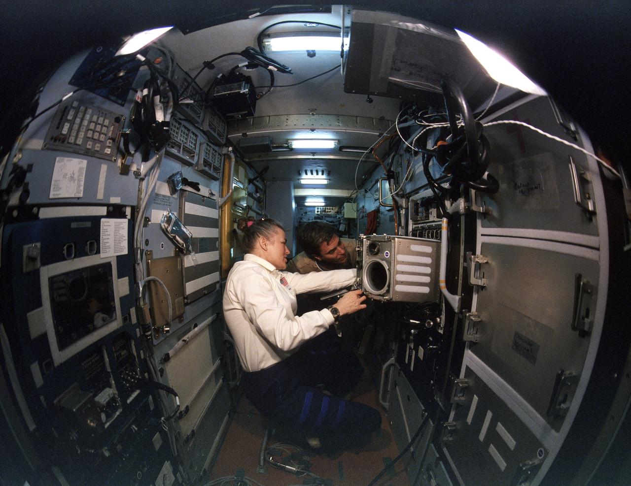 STS079-S-092 (16-26 Sept. 1996) --- Astronauts Shannon W. Lucid and John E. Blaha work at a microgravity glove box on the Priroda Module aboard Russia's Mir Space Station complex. Blaha, who flew into Earth-orbit with the STS-79 crew, and Lucid are the first participants in a series of ongoing exchanges of NASA astronauts serving time as cosmonaut guest researchers onboard Mir. Lucid went on to spend a total of 188 days in space before returning to Earth with the STS-79 crew.  During the STS-79 mission, the crew used an IMAX camera to document activities aboard the Space Shuttle Atlantis and the various Mir modules, with the cooperation of the Russian Space Agency (RSA).  A hand-held version of the 65mm camera system accompanied the STS-79 crew into space in Atlantis' crew cabin. NASA has flown IMAX camera systems on many Shuttle missions, including a special cargo bay camera's coverage of other recent Shuttle-Mir rendezvous and/or docking missions.