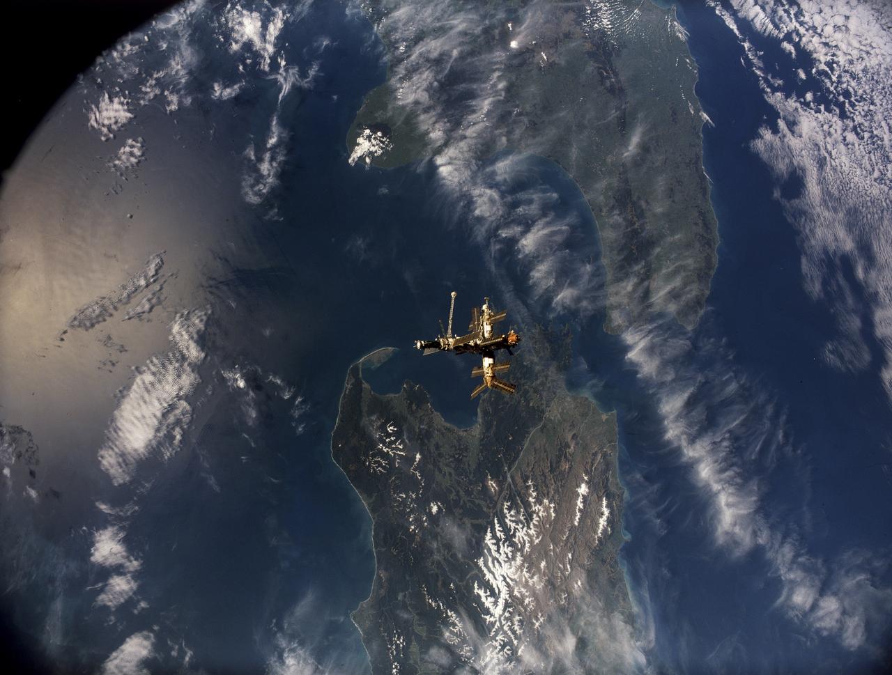 STS079-S-105 (16-26 Sept. 1996) --- Following undocking from the space shuttle Atlantis, Russia's Mir Space Station is backdropped over parts of both of New Zealand's main islands in this motion picture frame. Mt. Egmont and Cook Strait are geologic features that can be easily delineated in the image. During the STS-79 mission, the crew used an IMAX camera to document Intravehicular Activities (IVA) aboard the Space Shuttle Atlantis and the various Mir modules, as well as to record both docking and undocking activities through Atlantis' windows. NASA has flown IMAX camera systems on many Shuttle missions, including a special cargo bay camera's coverage of other recent Shuttle-Mir rendezvous and/or docking missions.