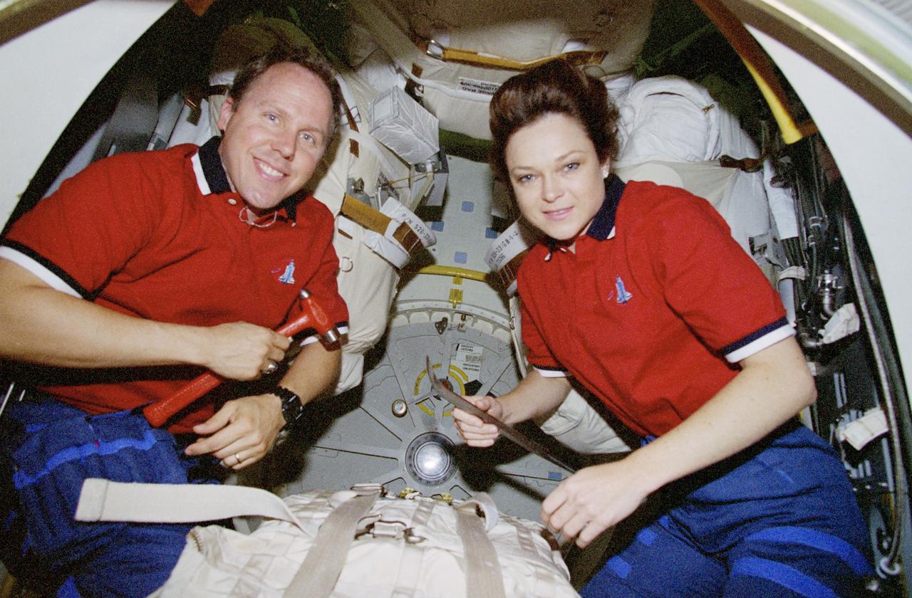 STS080-317-018 (28 Nov. 1996) --- Astronauts Thomas D. Jones, with a hammer, and Tamara E. Jernigan, holding a crow bar, display just two of the tools they called on during an intense effort to open the space shuttle Columbia's hatch leading to the cargo bay. Scheduled Extravehicular Activities (EVA) for the two were canceled by NASA when all efforts to open the hatch were unsuccessful.