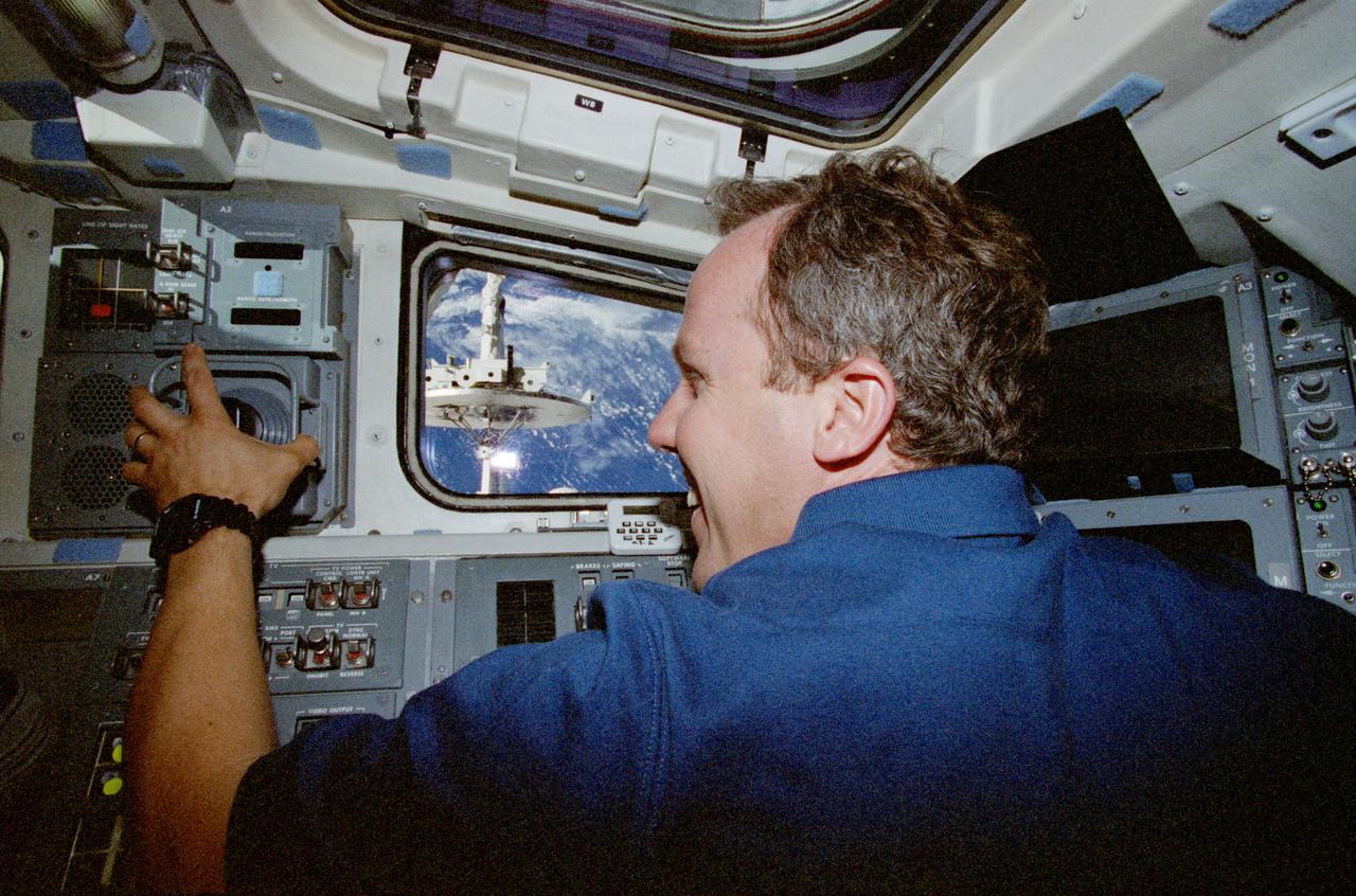 STS080-337-026 (19 Nov.-7 Dec. 1996) --- Astronaut Thomas D. Jones, STS-80 mission specialist, uses the controls of the space shuttle Columbia's Remote Manipulator System (RMS) to conduct a test with the captured Wake Shield Facility (WSF) seen through window at frame center.